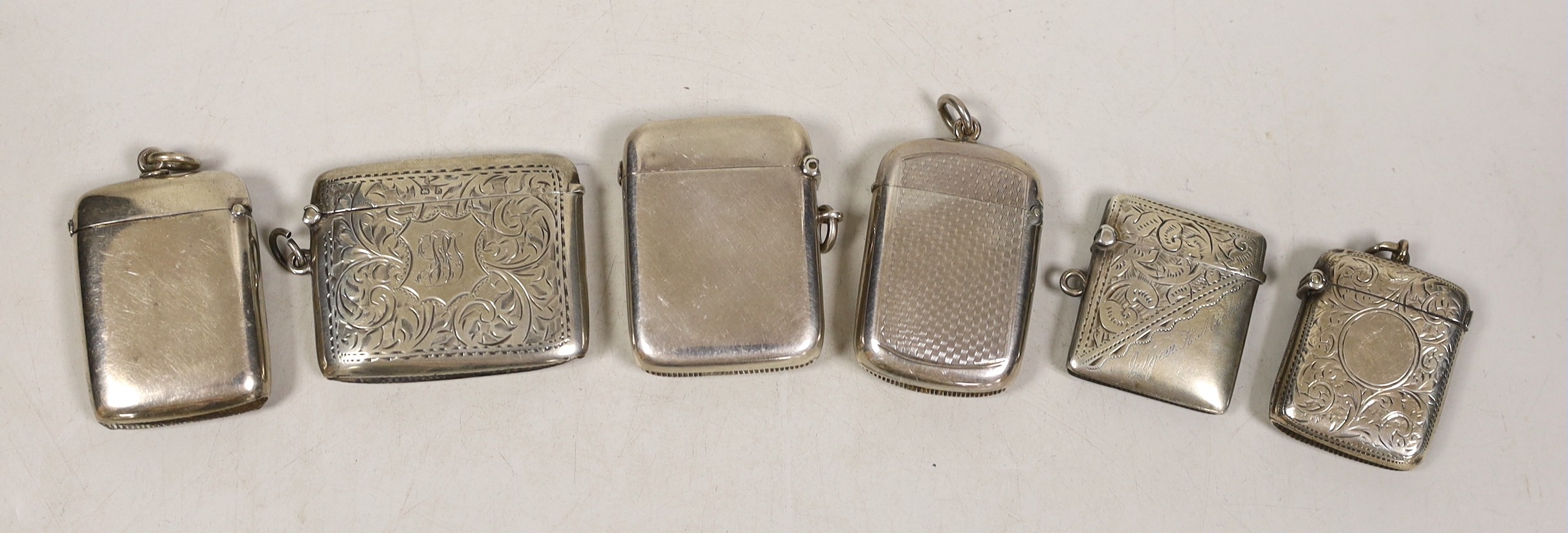 Six assorted mainly early 20th century engraved or engine turned silver vesta cases, largest 52mm.